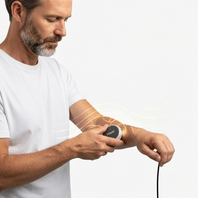 Person using a PEMF device on their arm, with subtle light waves emanating from the device